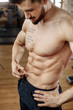 Muscular athletic young man bodybuilder fitness model measuring fat percent in gym. Perfect abs.