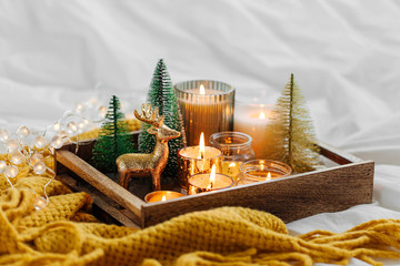 Wall Mural - Wooden tray with burning candles  and christmas decorations on with warm plaid. Winter cozy style. Hygge concept.