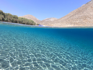 Above and below underwater photo of crystal clear turquoise beach of Kaminakia, Astypalaia island, Dodecanese, Greece