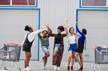 Wall Mural - Group of five african american woman with shopping carts having fun together outdoor.