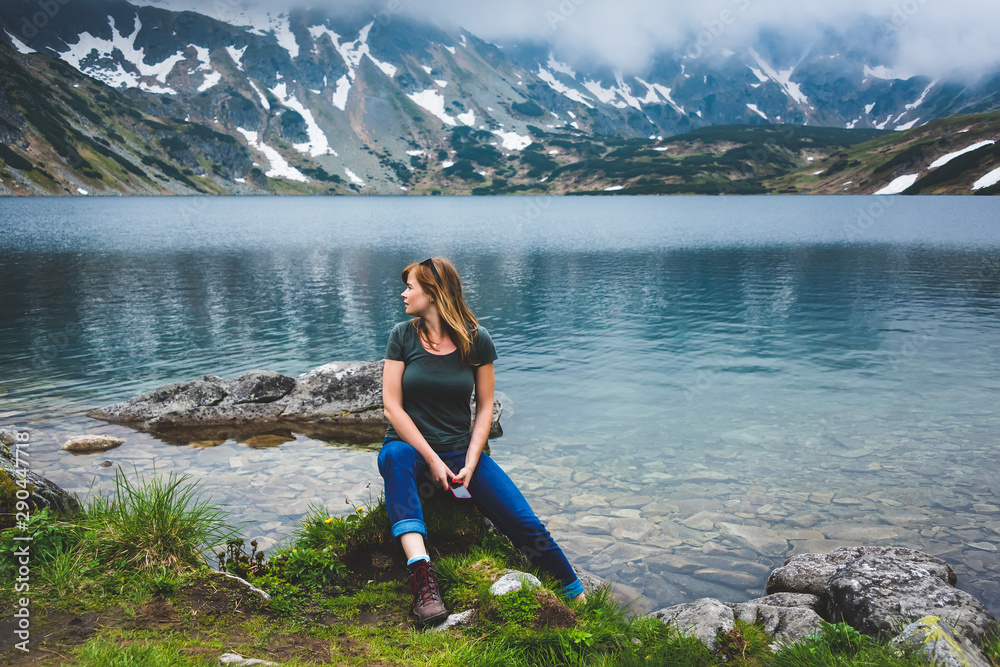 Young woman sit near Beautiful lake in Tatra mountains. Poland - obrazy, fototapety, plakaty 