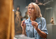 © JENOCHE - woman visitor looking at exhibition in museum of ancient sculpture.