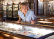 © JENOCHE - Woman visitor in the historical museum looking at art object.