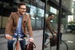 © NDABCREATIVITY - Happy young stylish businessman going to work by bike