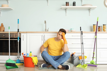 Sticker - Tired young man sitting on floor after cleaning kitchen