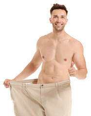 Sticker - Handsome muscular man in loose pants on white background. Weight loss concept