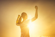 © kieferpix - Strong, confident, determined woman flexing her muscles facing sunset.