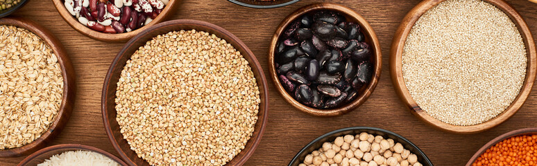 Sticker - panoramic shot of bowls with oatmeal, buckwheat, quinoa, beans and chickpea on wooden surface