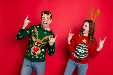 Poster - Portrait of foolish two family people wife husband brown hair scream have rock-and-roll show horned sign wear rudolf christmas tree design costume pullover sweater isolated over red color background