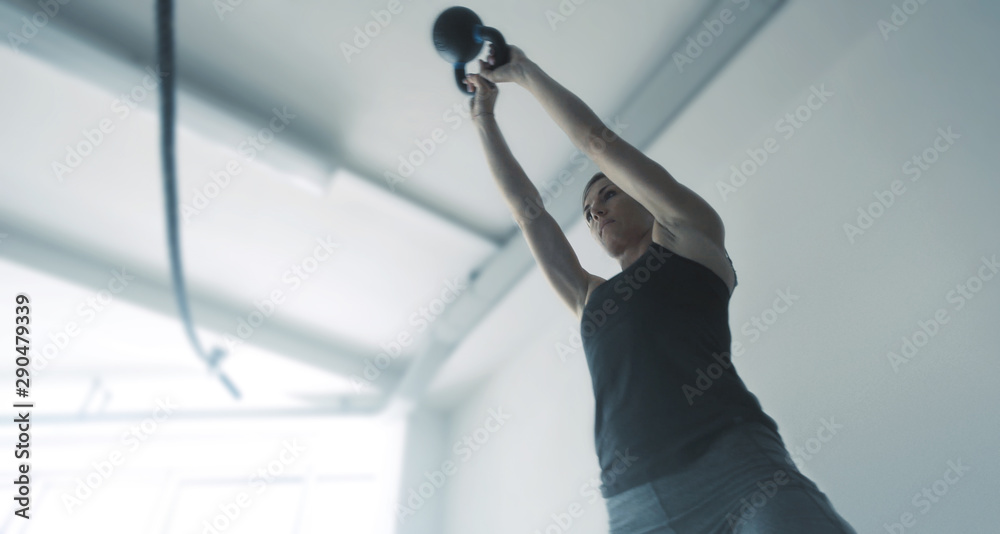 Fit muscular woman exercising with a kettlebell - obrazy, fototapety, plakaty 