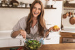 © Drobot Dean - Happy positive cute beautiful woman indoors at the kitchen cooking.
