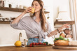 © Drobot Dean - Pleased cute beautiful woman indoors at the kitchen cooking drinking juice.