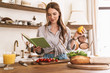 © Drobot Dean - Woman indoors at the kitchen cooking holding notebook and lemon.
