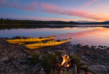 Fototapete - Campfire during dusk at the shore of a lake with two kayaks. Jamtland, Sweden.