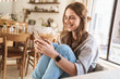 © Drobot Dean - Smiling cheerful beautiful redhead woman at home using mobile phone.