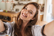 © Drobot Dean - Beautiful happy ginger woman indoors at home take selfie by camera.
