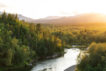 Fotobehang - The sun setting over a river in a   mountain wilderness.  Jamtland, Sweden.