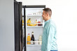 © Syda Productions - eating and diet concept - smiling middle-aged man looking for food in fridge at kitchen