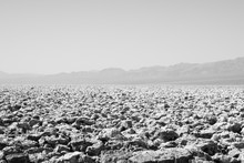 Black And White View Of A Vast Death Valley Landscape, Rock Formations And The Badwater Basin Salt Deposits.