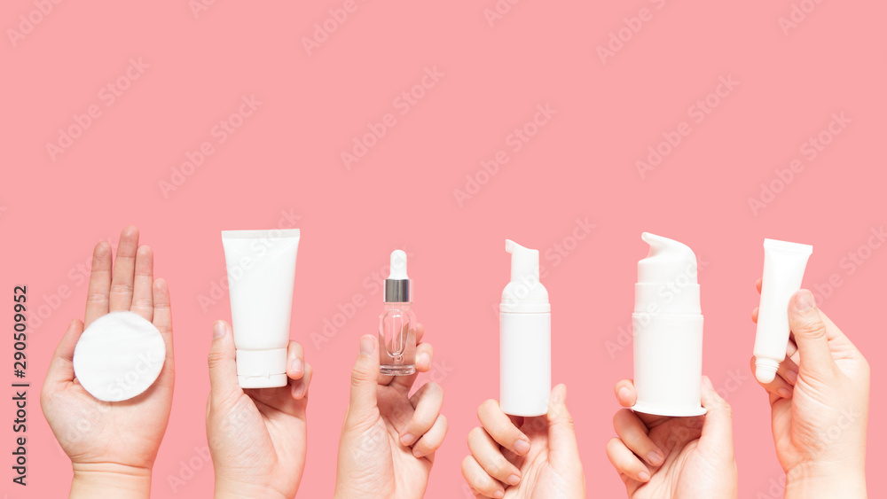 Skincare routine step for healthy skin - Woman hands holding facial cotton pad, foam, essential oil, serum, lotion and eye cream packaging on pink background. Beauty and cosmetic concept. Copy space. - obrazy, fototapety, plakaty 
