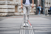 Midsection Of Young Blind Man With White Cane Walking Across The Street In City.