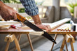 © francescomou - Adult craftsman carpenter with manual saw working on cutting a wooden table. Housework do it yourself. Stock photography.