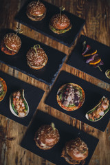 A close up shot of a selection of canape dishes. Concept of catering, hospitality and lifestyle. Small snacks and nibbles served on black slates for a private reception.