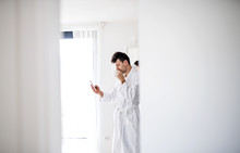 Young Man With Coffee And Smartphone In The Bedroom, A Morning Routine.