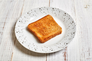 Toasted white toast on a plate on a light wooden background.