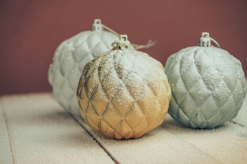 Poster - Beautiful Christmas baubles on a new wooden table fell by snow and dark red wall background behind.