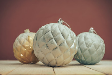 Poster - Beautiful Christmas baubles on a new wooden table fell by snow and dark red wall background behind.