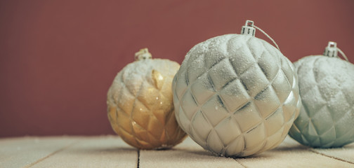 Poster - Beautiful Christmas baubles on a new wooden table fell by snow and dark red wall background behind.