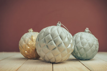 Poster - Beautiful Christmas baubles on a new wooden table fell by snow and dark red wall background behind.