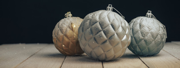 Poster - Beautiful Christmas baubles on a new wooden table fell by snow and dark red wall background behind.