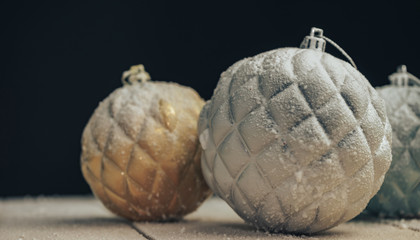 Poster - Beautiful Christmas baubles on a new wooden table fell by snow and black  background behind.