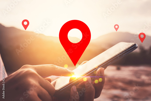 Fotomural Woman hand using smart phone on top of mountain with navigator location point abstract background