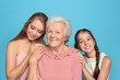 © New Africa - Happy sisters with their grandmother on light blue background