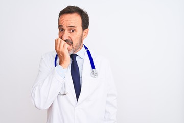 Poster - Middle age doctor man wearing coat and stethoscope standing over isolated white background looking stressed and nervous with hands on mouth biting nails. Anxiety problem.