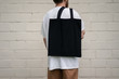 © Elena - Man holding cotton Black Tote bag
