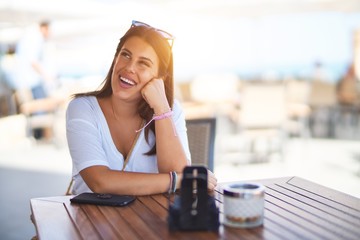 Young beautiful woman sitting at terrace of a restaurant smiling