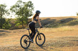 © Mountains Hunter - Girl on a mountain bike on offroad, beautiful portrait of a cyclist at sunset, Fitness girl rides a modern carbon fiber mountain bike in sportswear, a helmet, glasses and gloves.