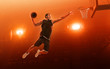 © TandemBranding - African american professional basketball player on basketball court in action with the ball. Slam Dunk. Red floodlit background