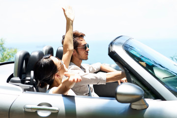 asian couple riding in convertible car