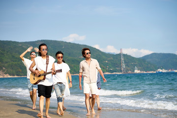 members of a rock band walking on beach