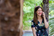 © pablobenii - Woman laughing and speaking on smartphone in park