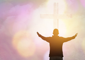 soft focus and Silhouettes of man raise hand up worship God over the cross in cloudy sky . Christian background with copy space for your text