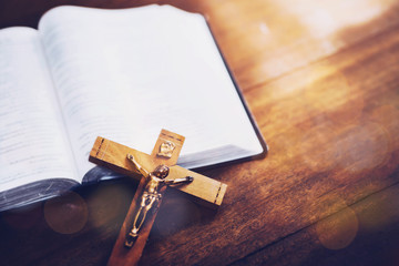 Wall Mural - Close up of Jesus's crucifix over bible on wooden table background, copy space