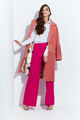 Wall Mural - High fashion portrait of young elegant woman. Coral coat, magenta pants, white blouse.