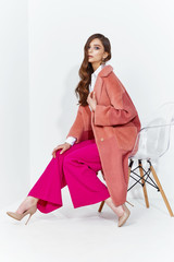 Wall Mural - High fashion portrait of young elegant woman. Coral coat, magenta pants, white blouse.