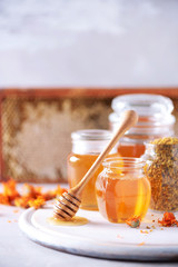 Wall Mural - Herbal honey in jar with dipper, honeycomb, bee pollen granules, calendula flowers on grey background.